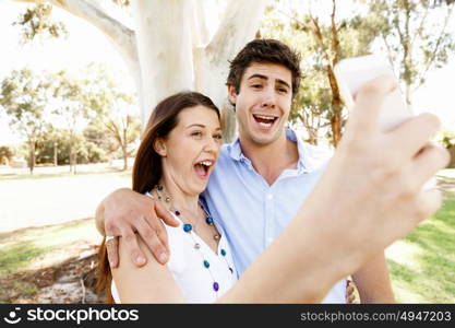 Young couple in the park. Young couple in the park making their selfi with mobile phone