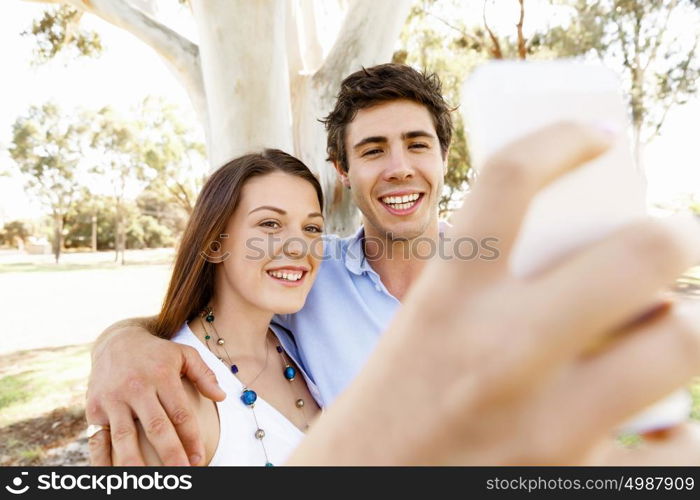 Young couple in the park. Young couple in the park making their selfi with mobile phone