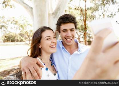 Young couple in the park. Young couple in the park making their selfi with mobile phone