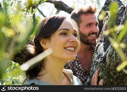 Young couple in tree looking away smiling