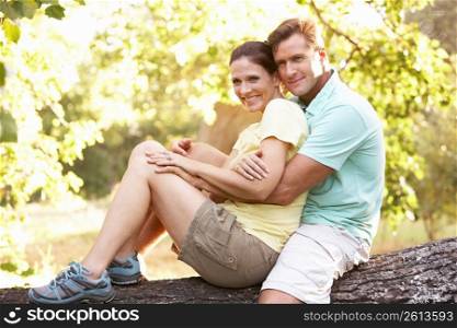 Young Couple In Walking Clothes Resting On Tree In Park