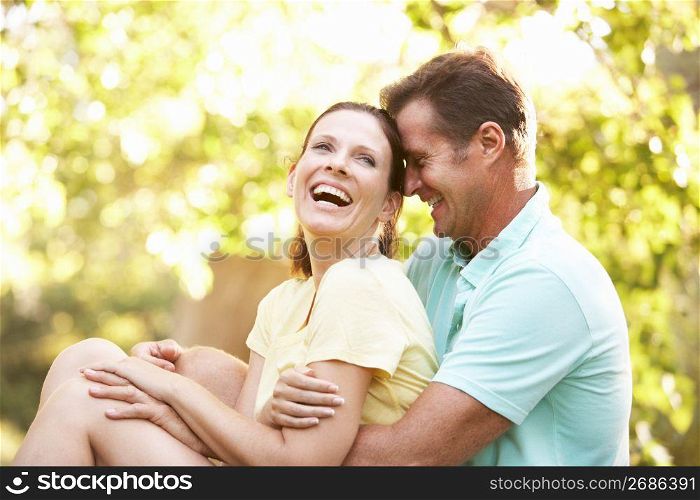 Young Couple In Walking Clothes Resting On Tree In Park
