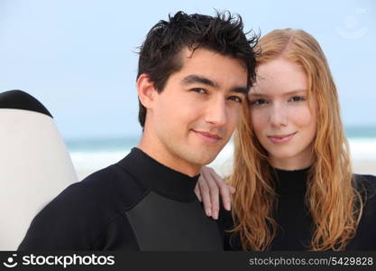 Young couple in wetsuits at the beach