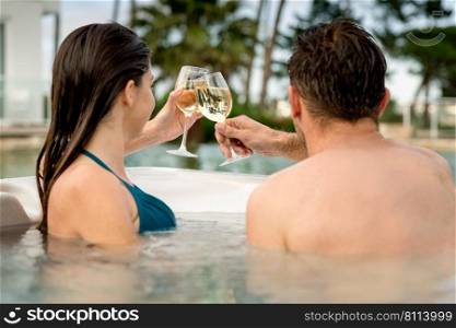 Young couple inside a jacuzzi and toasting 