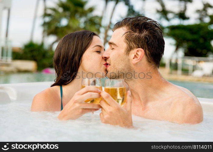 Young couple inside a jacuzzi dating and toasting 