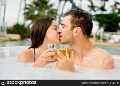 Young couple inside a jacuzzi dating and toasting 