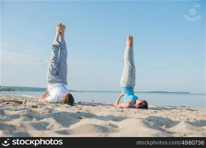 Young couple is practicing yoga at beach