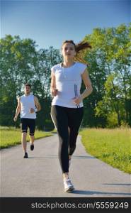 Young couple jogging in park at morning. Health and fitness concept