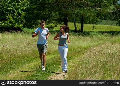 Young couple jogging outdoors in spring nature on sunny day