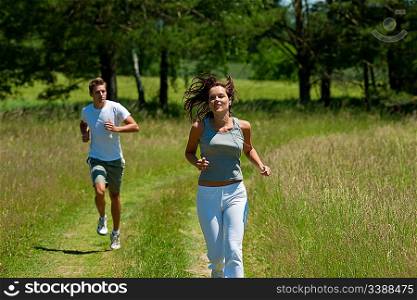 Young couple jogging outdoors in spring nature on sunny day