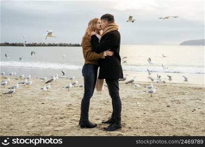 young couple kissing winter by beach