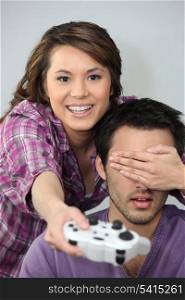 Young couple larking about with a games console