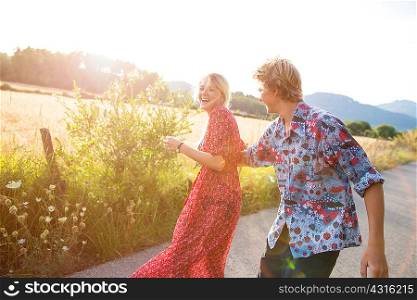 Young couple laughing and fooling around on rural road, Majorca, Spain