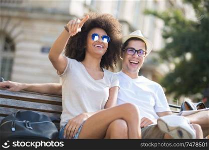 young couple laughing while sitting on the bench