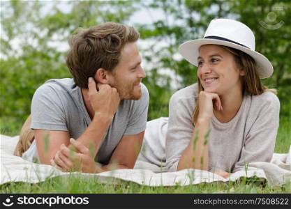 young couple layed on blanket on the grass