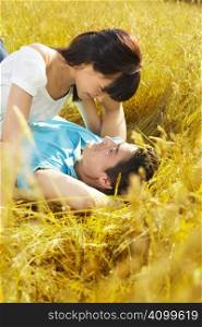 young couple laying down in meadow and hugging