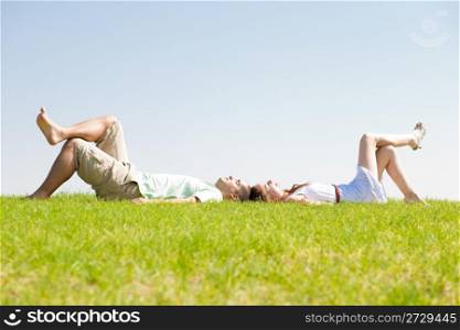 young couple lie down on grass, outdoor at park..