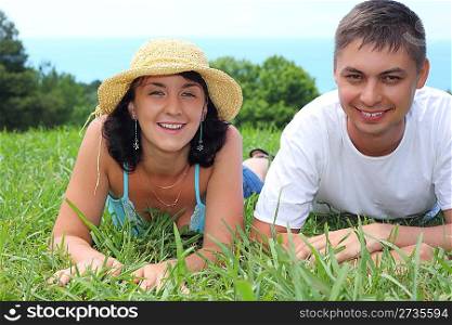 young couple lies on grass near sea