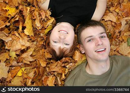 young couple lies on yellow leaves