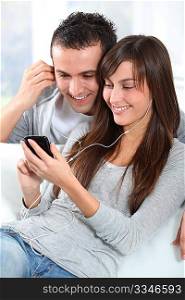 Young couple listening to music with mobile phone