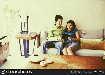 Young couple looking at a picture frame and smiling on a couch