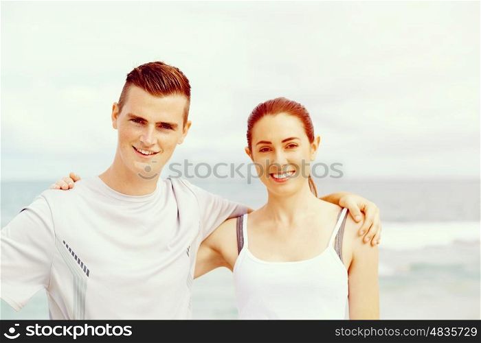Young couple looking at camera standing on beach. Young couple looking at camera while standing together on beach