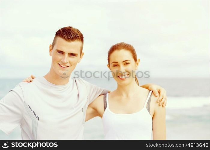 Young couple looking at camera standing on beach. Young couple looking at camera while standing together on beach