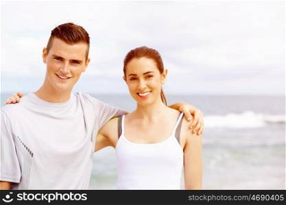 Young couple looking at camera while standing on beach. Young couple looking at camera while standing together on beach