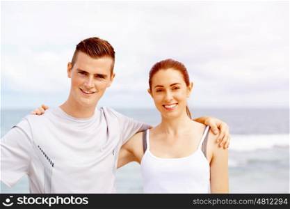 Young couple looking at camera while standing on beach. Young couple looking at camera while standing together on beach