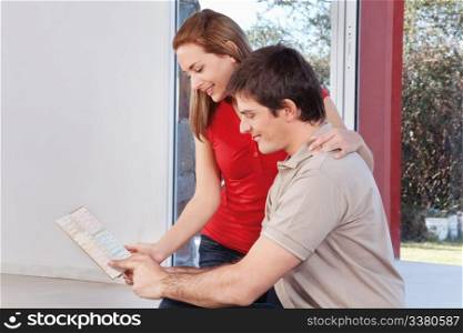 Young couple looking at color guide together in room