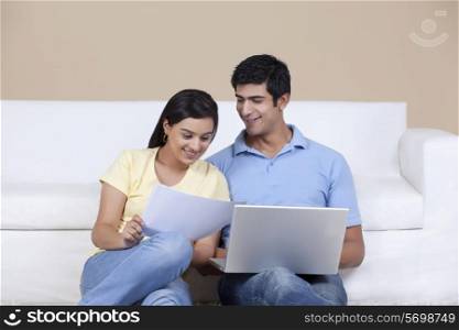 Young couple looking at document while using laptop