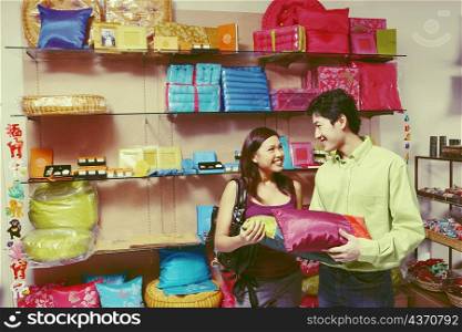 Young couple looking at each other and choosing pillows in a store