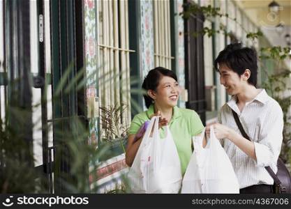 Young couple looking at each other and holding plastic bags