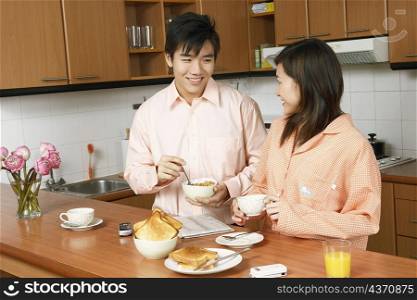 Young couple looking at each other and smiling at a kitchen counter