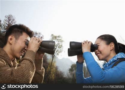Young couple looking at each other through binoculars