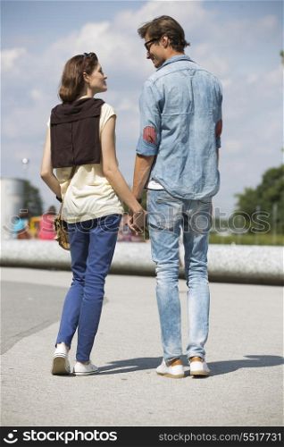 Young couple looking at each other while holding hands on street