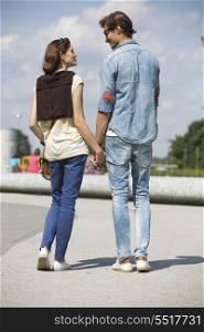 Young couple looking at each other while holding hands on street