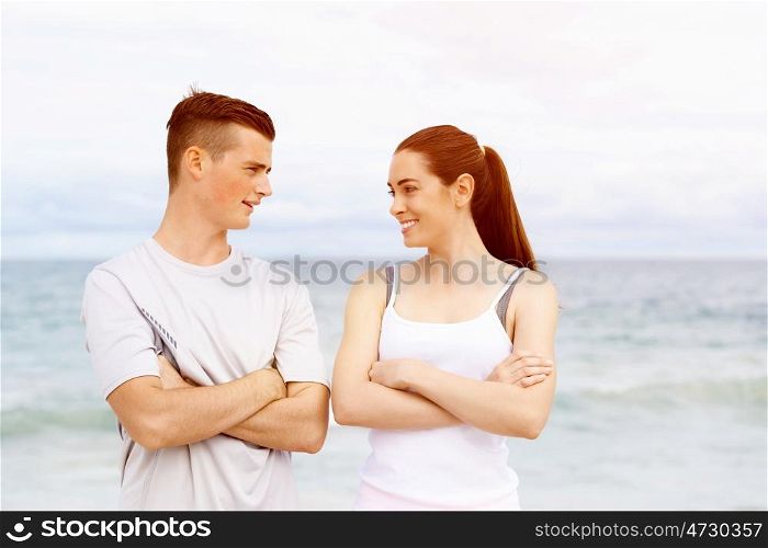 Young couple looking at each other while standing on beach. Young couple looking at each other while standing together on beach