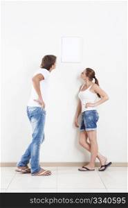 Young couple looking at hanging on the wall frame
