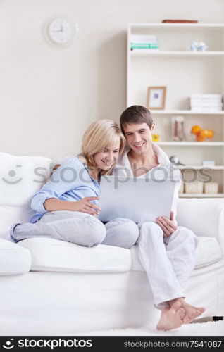 Young couple looking at laptop on sofa