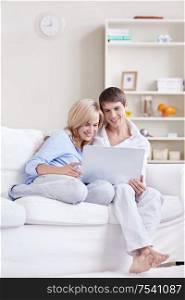 Young couple looking at laptop on sofa