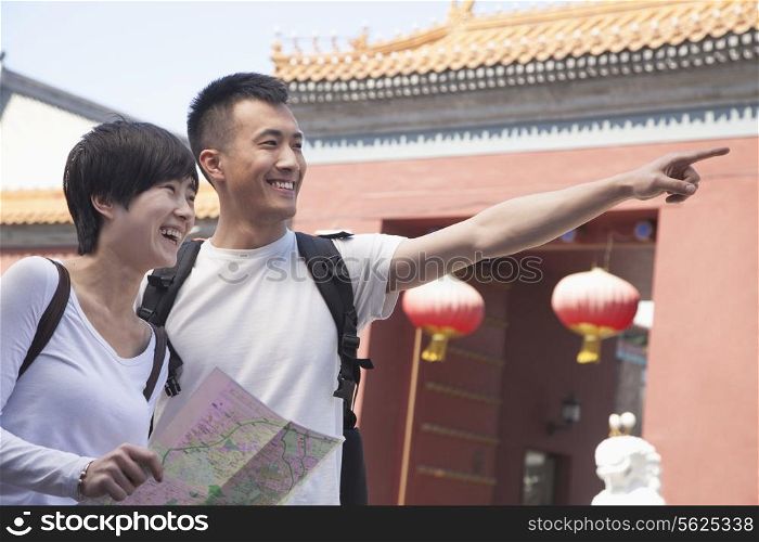 Young couple looking at map and pointing.