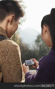 young couple looking at the picture on the screen of digital camera