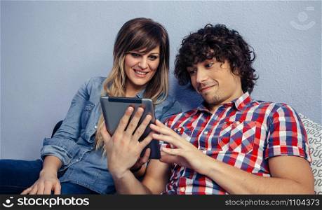 Young couple looking at the tablet sitting on the bed
