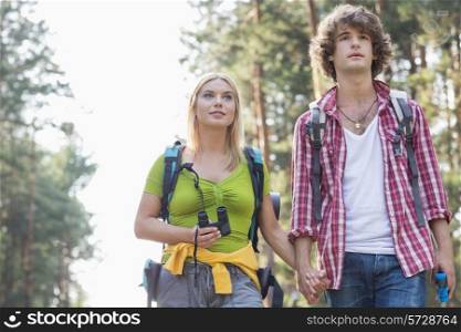 Young couple looking away while hiking in forest