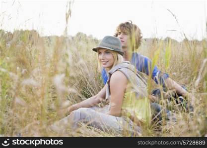 Young couple looking away while relaxing in field