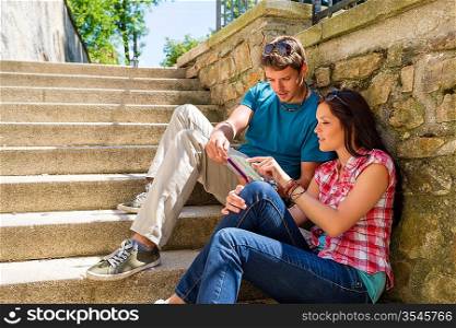 Young couple looking city map sunny day sitting stairs together
