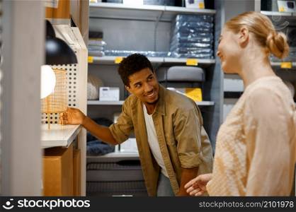 Young couple looking for new bedside lamp in shop trying table light sample in showcase. Young couple looking for bedside lamp in shop