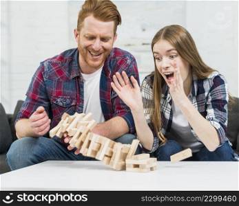 young couple looking jenga tower collapses white table surface