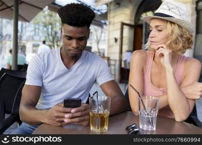 young couple looking smartphone in bar terrace